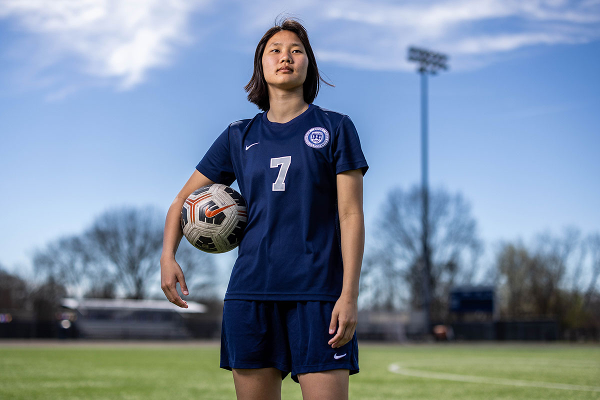 Sydney Lenhart wearing a soccer uniform and holding a soccer ball under her arm