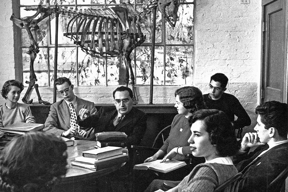 Black and white photo of a classroom in the 1950s. A large animal skeleton is seen in the background.