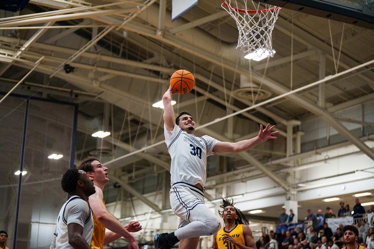 A basketball player leaps in the air to dunk the basketball
