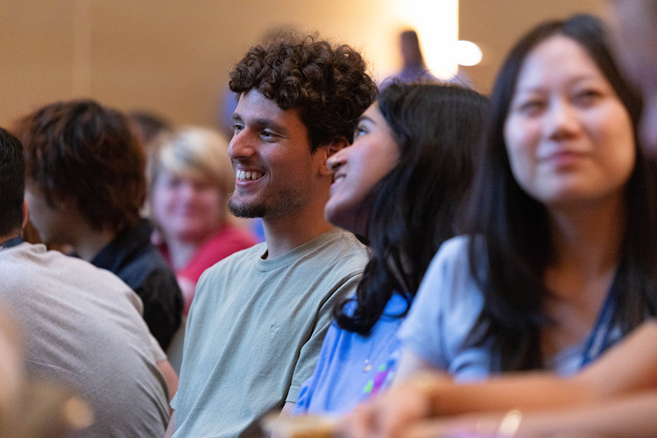 Two students speak together in the audience.