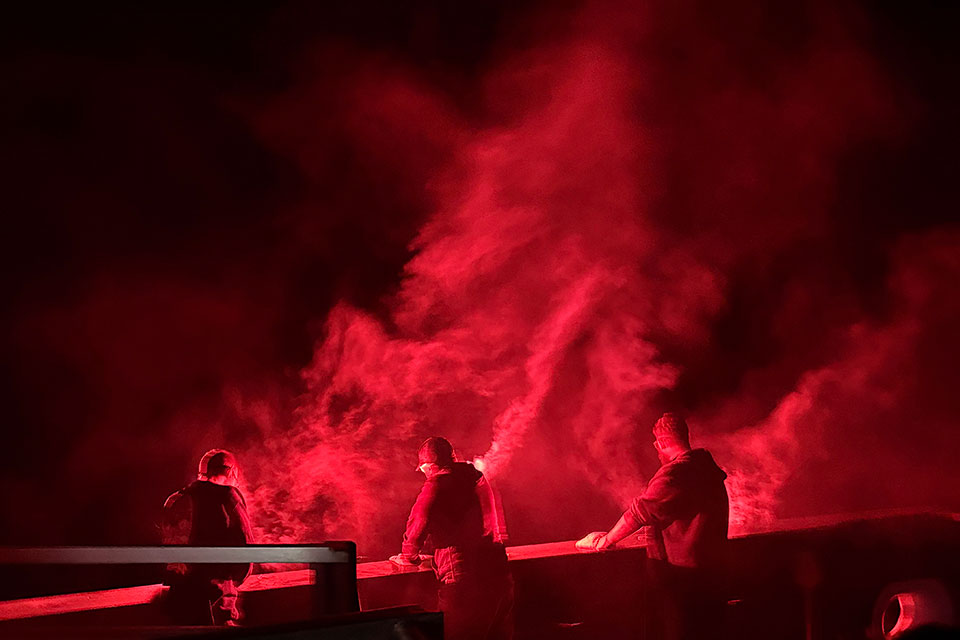 Researchers look over the edge of a NOAA research ship at night.