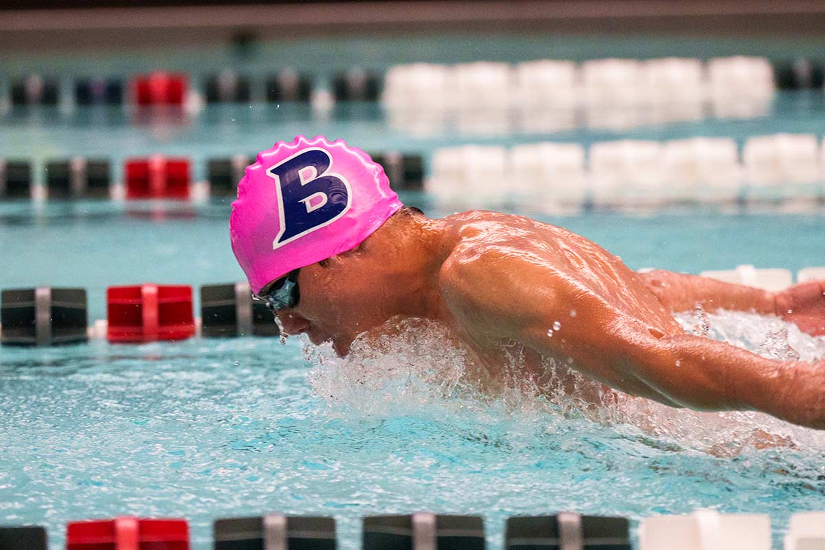 A person swimming with a bright pink cap
