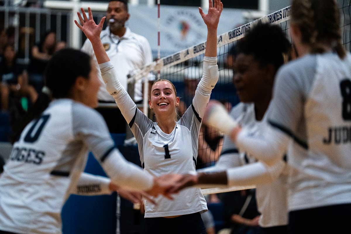 A volleyball player celebrates with hands raised
