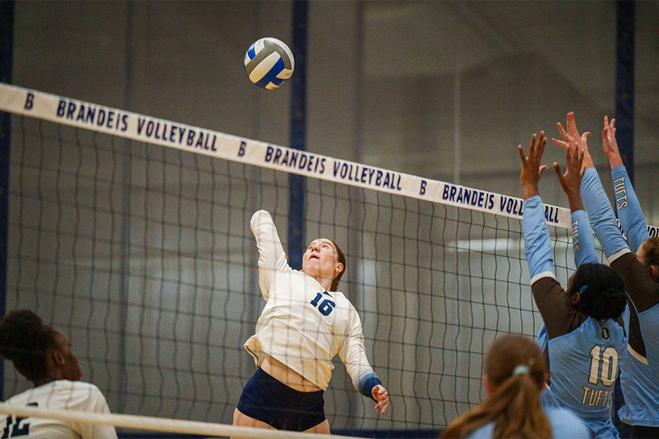 A volleyball player jumps to hit the ball over the net.