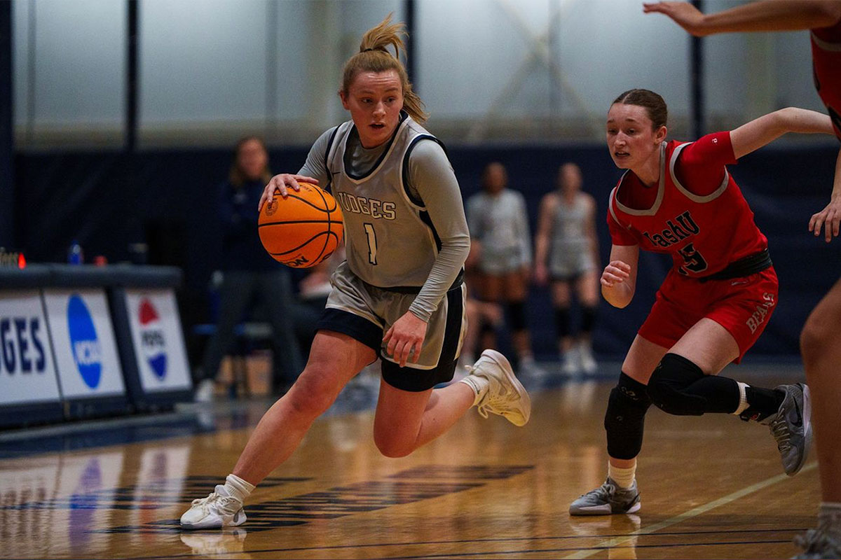 A Brandeis basketball player dribbles a basketball on a court.