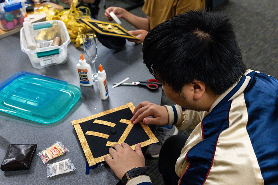 A student decorates their graduation mortarboard.