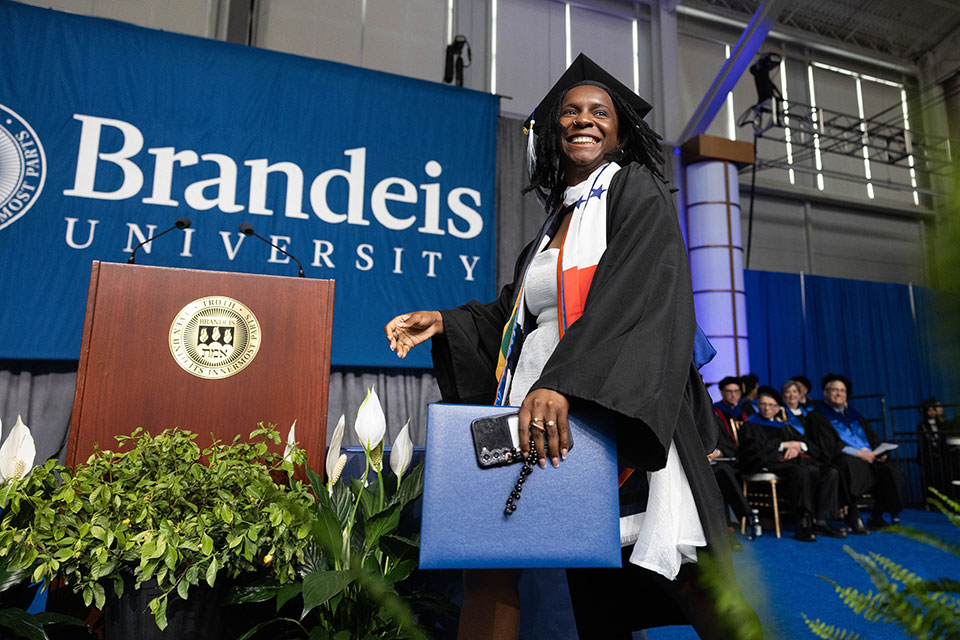 A graduating student dressed in academic regalia walks across the stage with a degree in hand during Commencement.