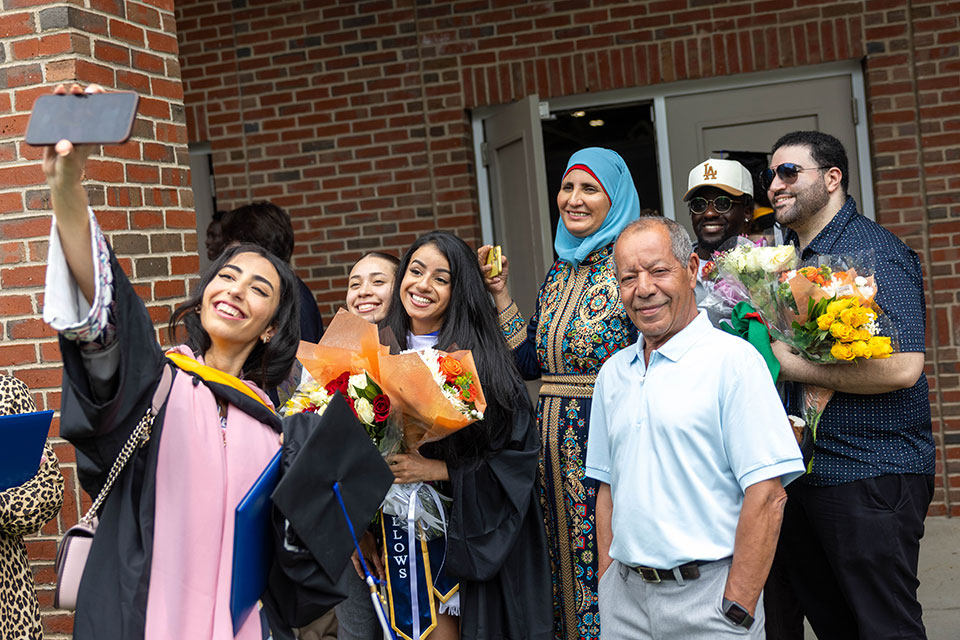 Graduating students take a selfie with their family outside after the Commencement ceremony.