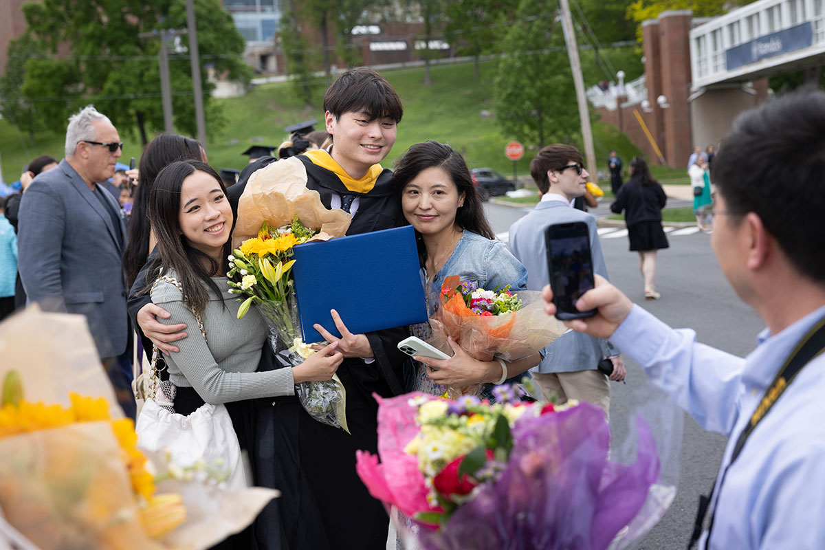 A graduating student poses for a photo with his family outside after the Commencement ceremony.