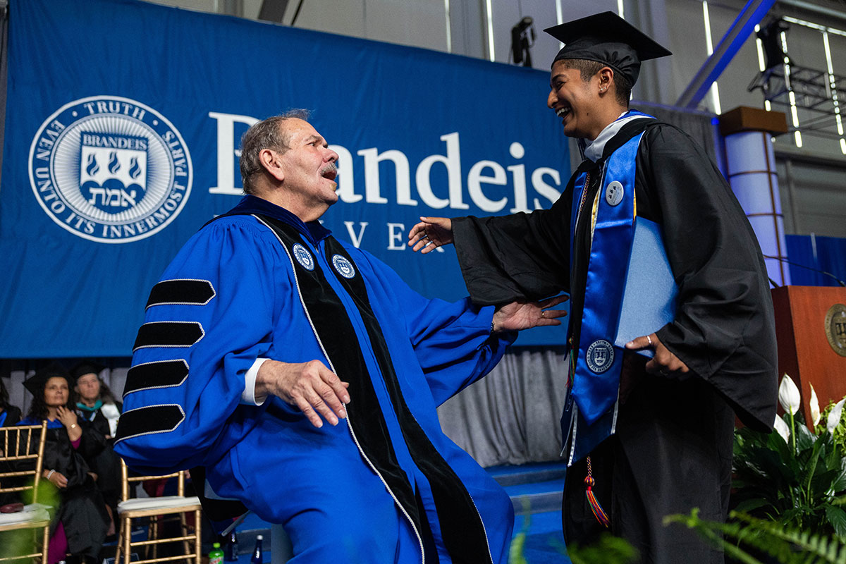 A graduating student moves to give President Levine a hug on stage during Commencement.