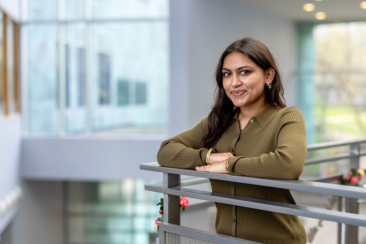 Samra wears a green shirt and leans on a railing.