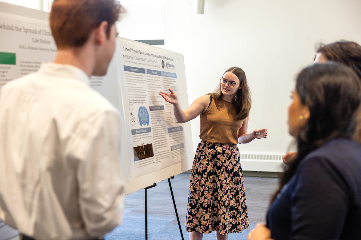 A woman presenting a scientific poster to an audience