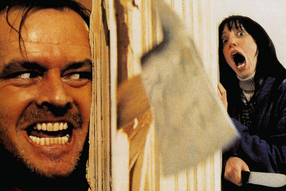 A scene from "The Shining" of a woman screaming and a man breaking through a door with an axe.