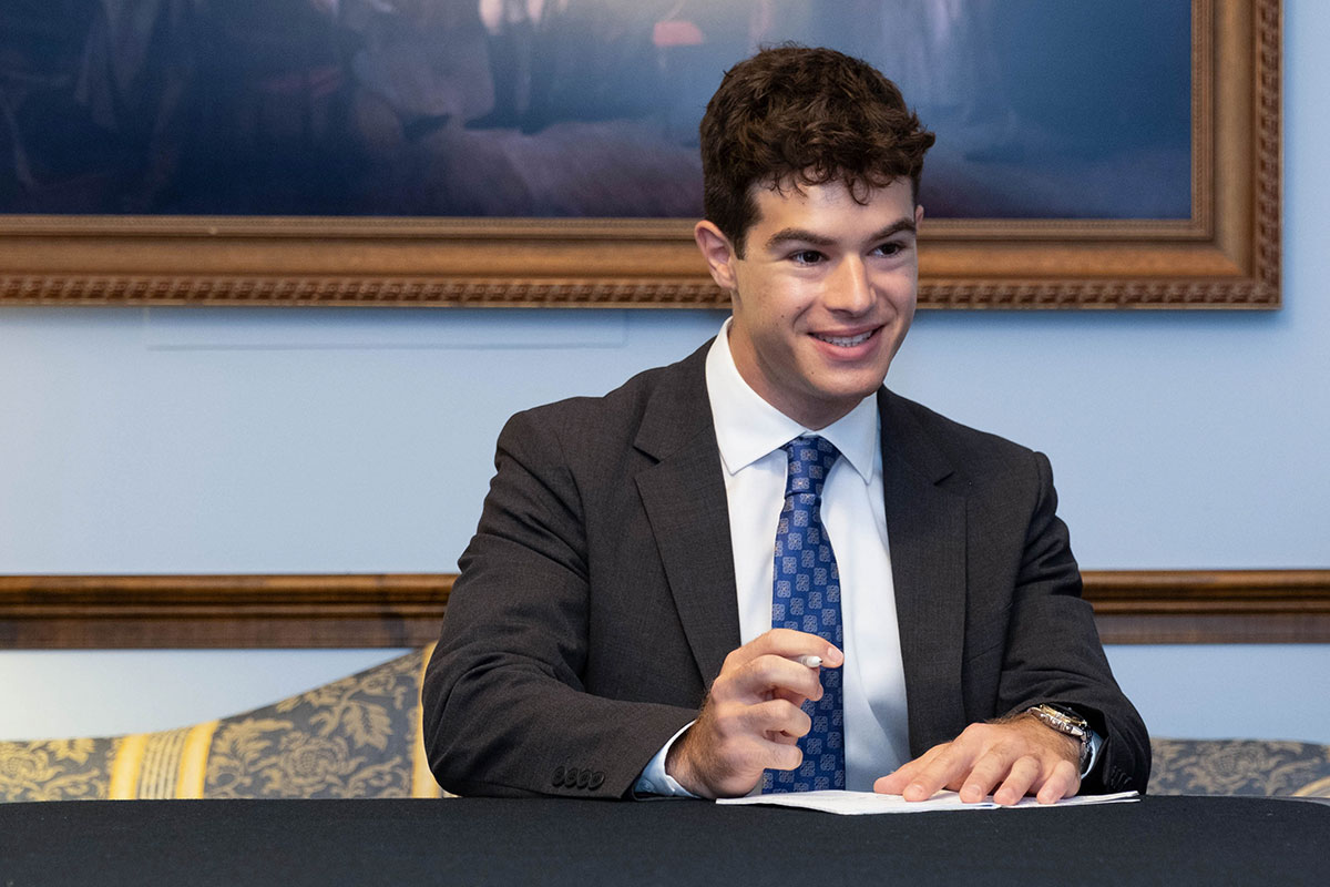 Noah Levy sitting at a table writing on a document.