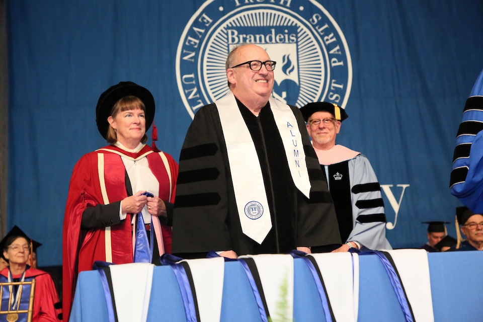 three people in cap and gown at a graduation ceremony.