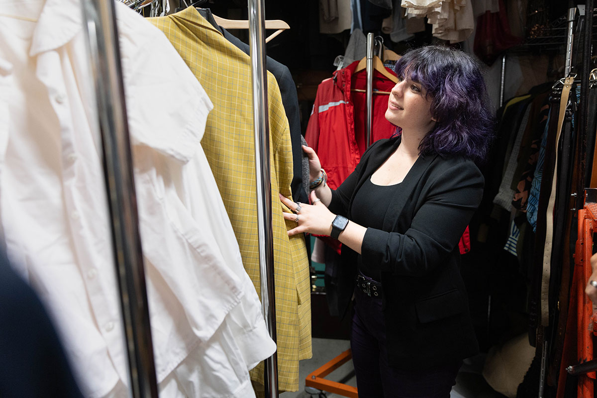 Jae Fioribello sorts through a clothing rack of costumes.