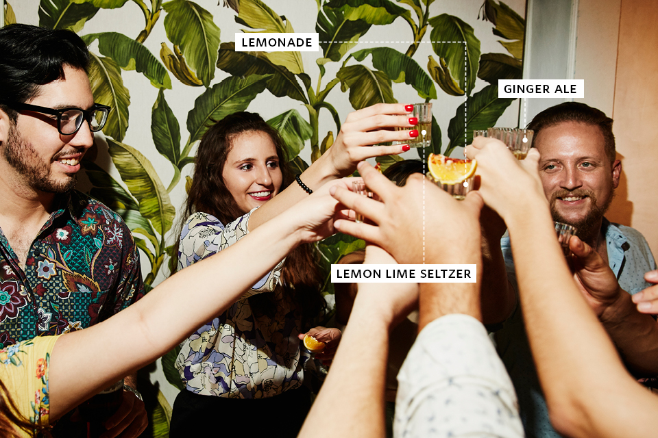 A group of young people hold up non-alcoholic drinks at a party to make a toast.