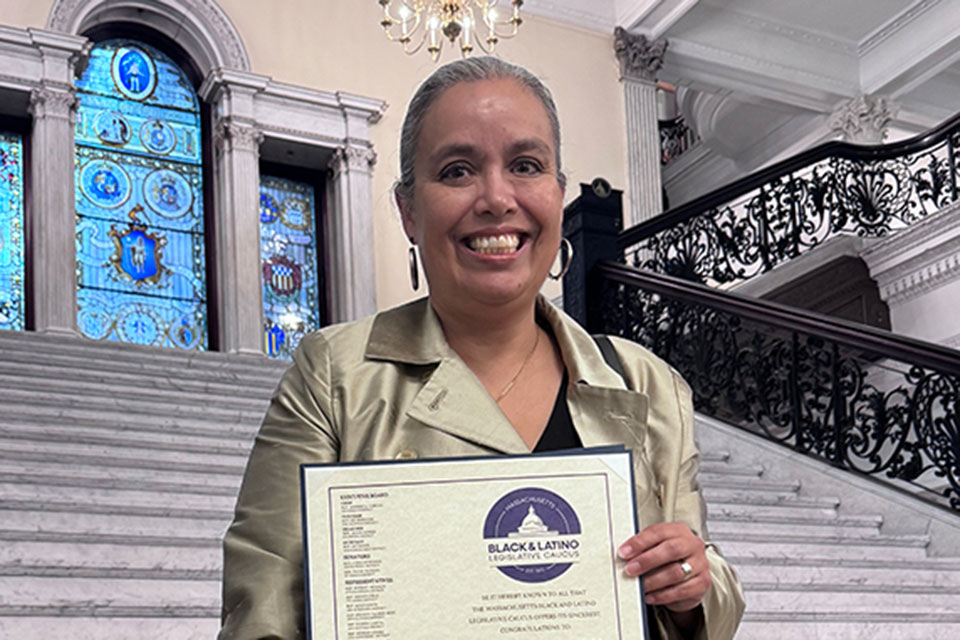 Alexandra Piñeros Shields holding an award inside the Massachusetts state house.