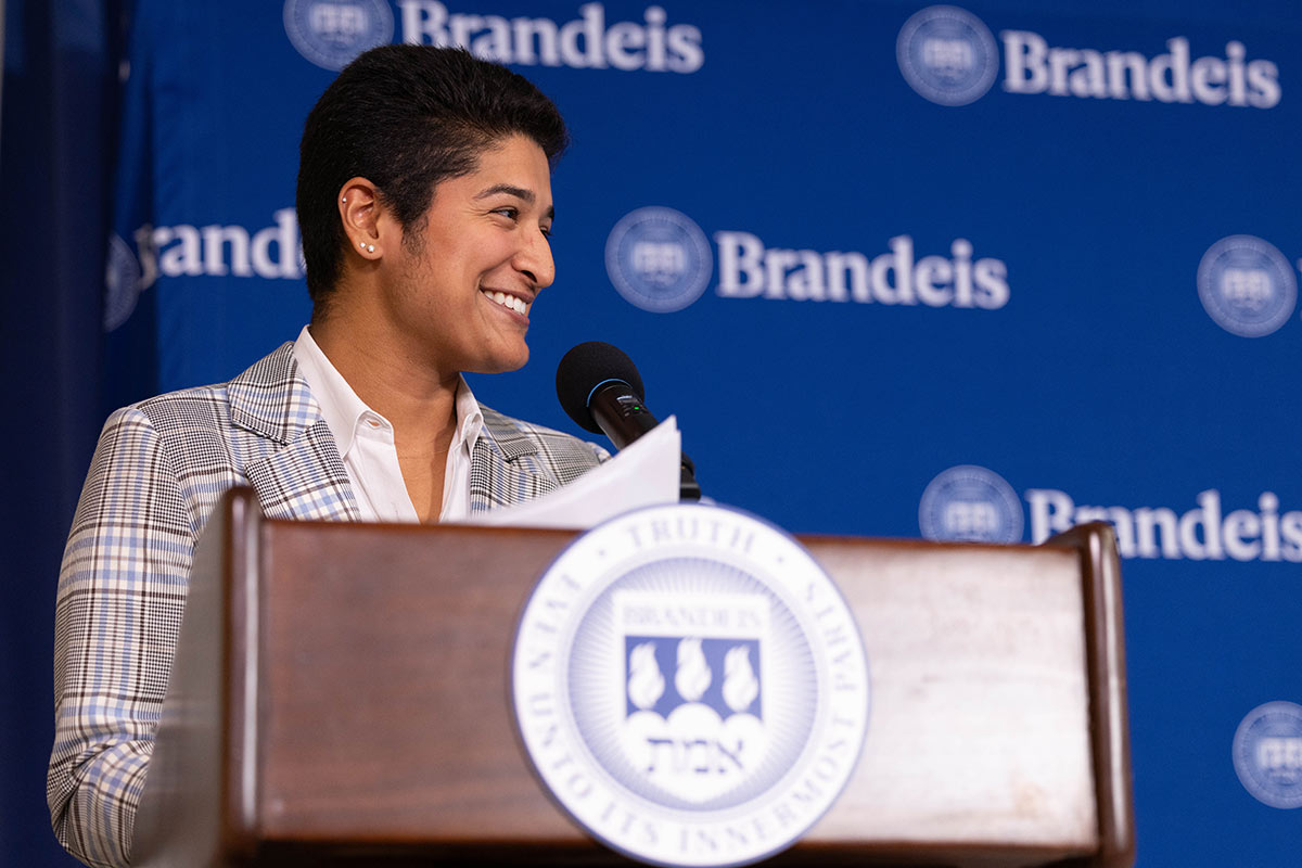 Rani stands and smiles at a podium while speaking at the event.