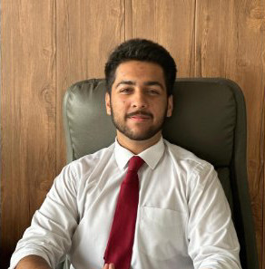 A male college student in a tie sitting at a desk