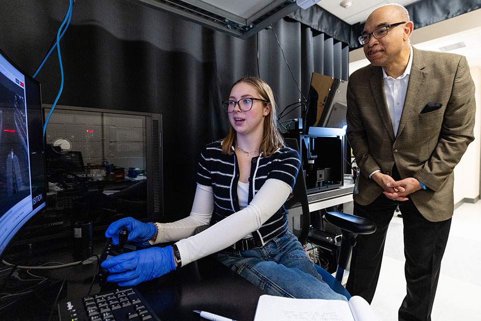Student at microscope with official looking on