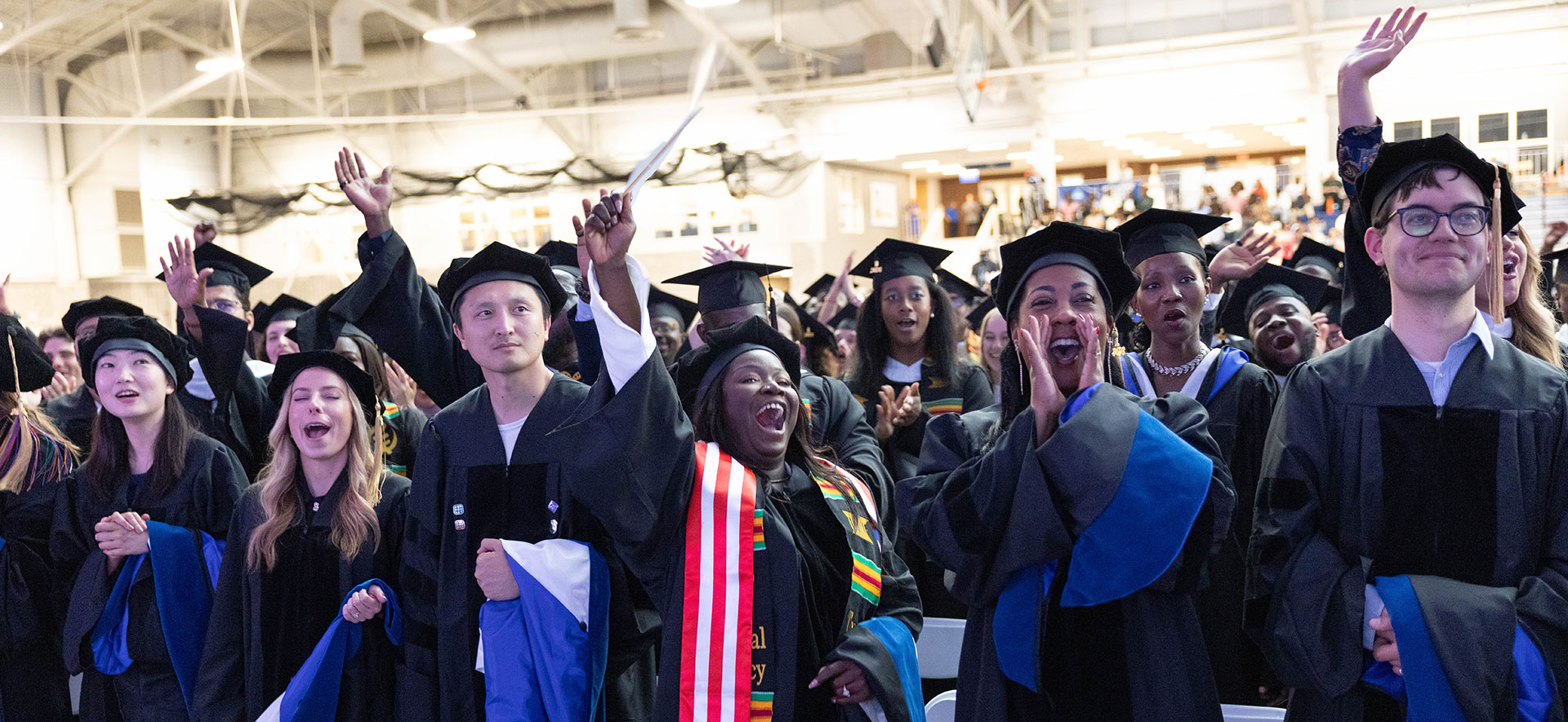 An audience of graduate students applaud and celebrate.