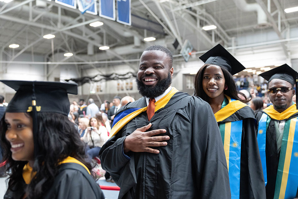 Graduating students smile at the graduate commencement ceremony.