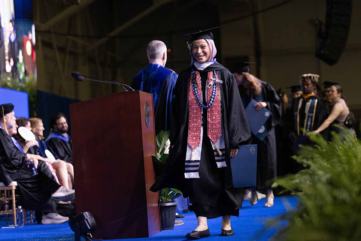 A graduate smiles while walking across the stage