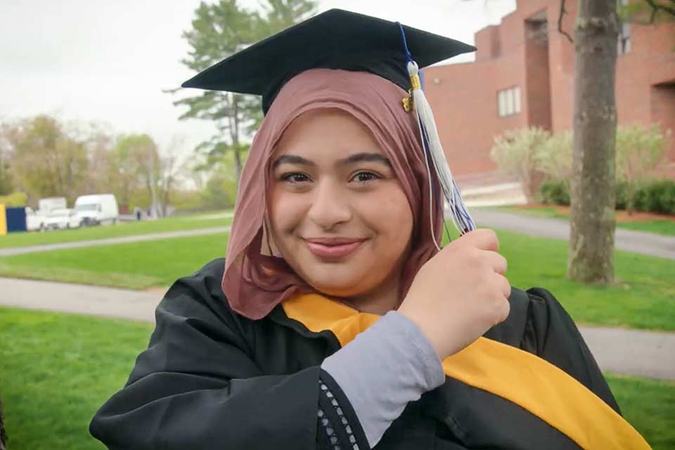 A graduate smiling on campus