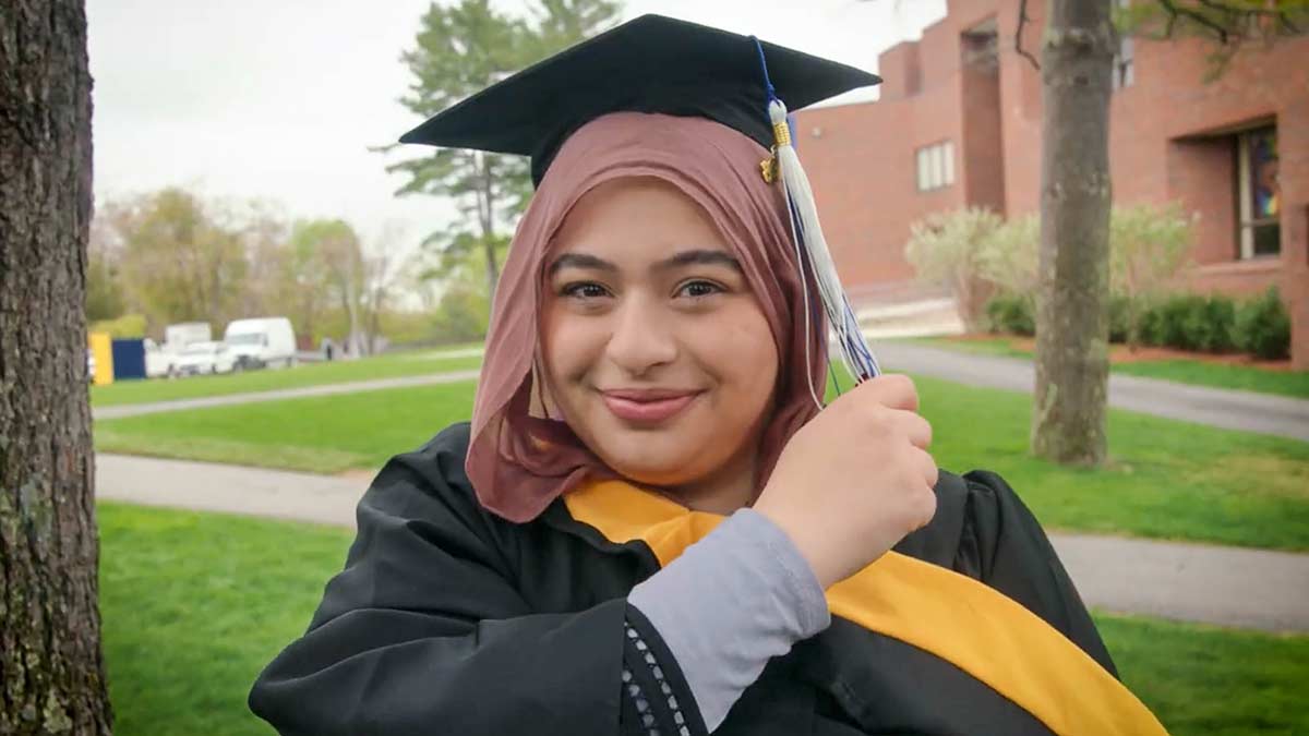 A graduate smiling on campus