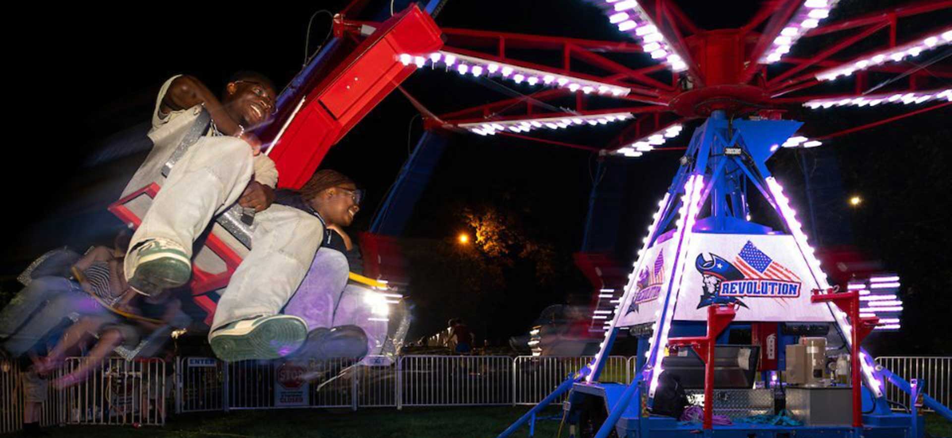 Two people riding a spinning carnival ride.