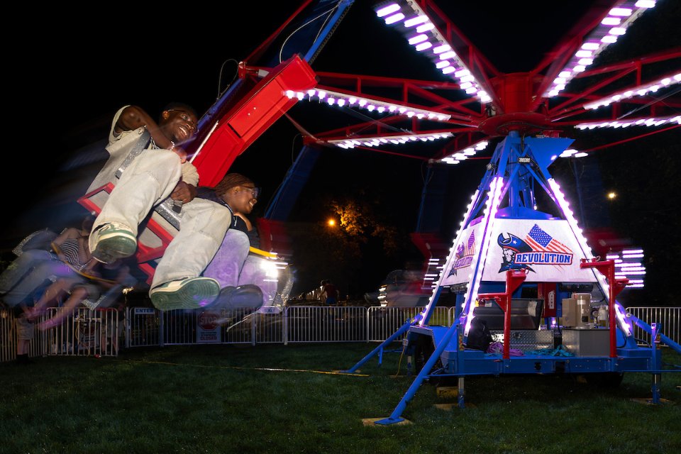 Two people riding a spinning carnival ride.