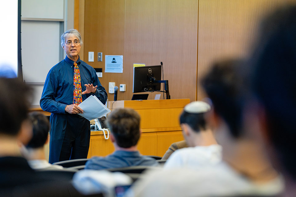 A professor speaks to a classroom full of students.