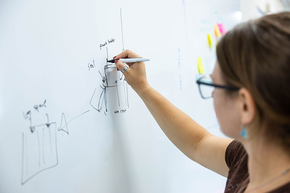 A student writes on a white board.