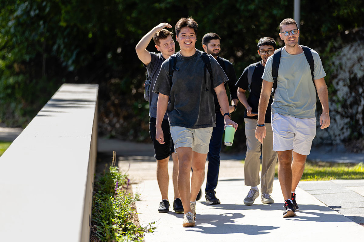 A group of students walk together along a path on campus.