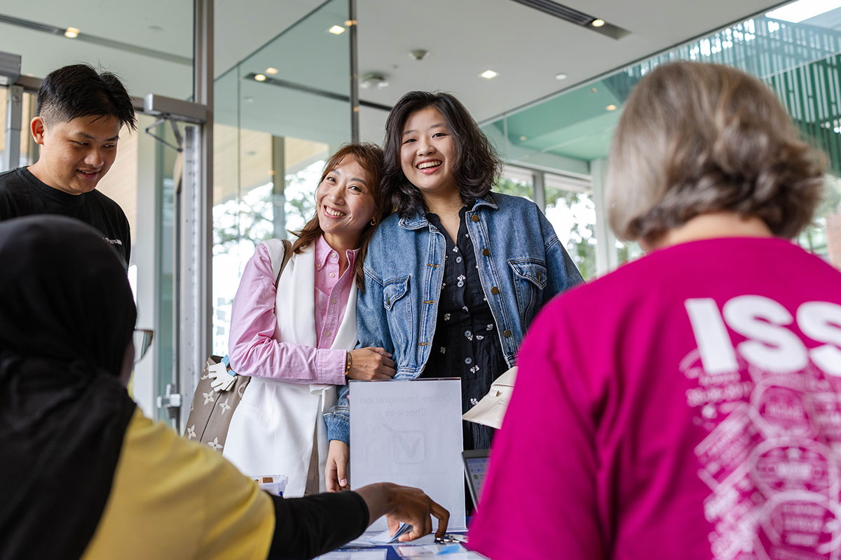 A mother and daughter smile in front of a move-in check-in table.