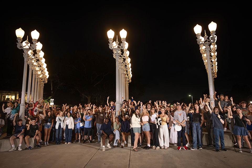 A large group of students poses for a photo in front of the "Light of Reason" sculpture.