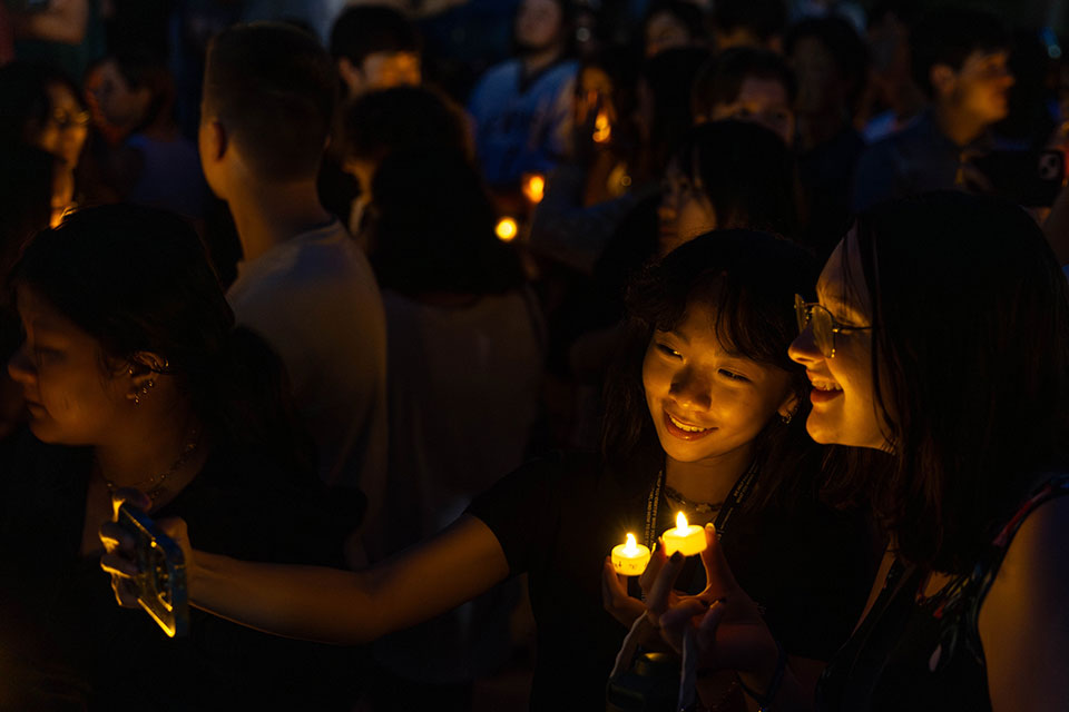 Two students hold candles and take a selfie.