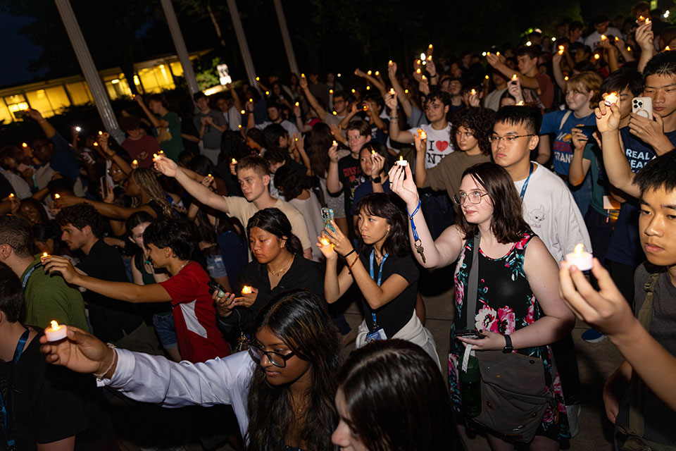 A large group of students stand together holding candles during Light the Night.