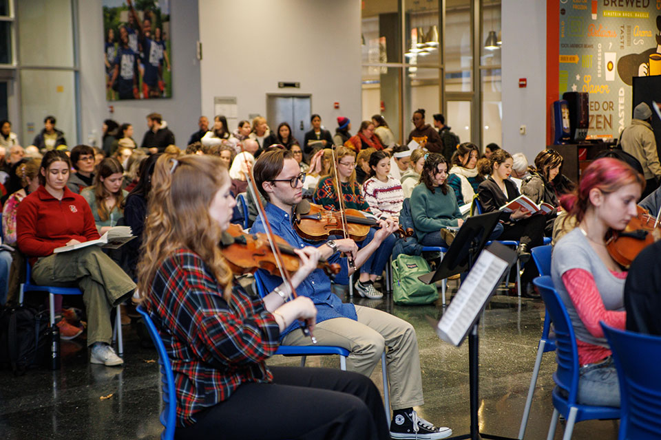 A group of people sing together while an orchestra plays.