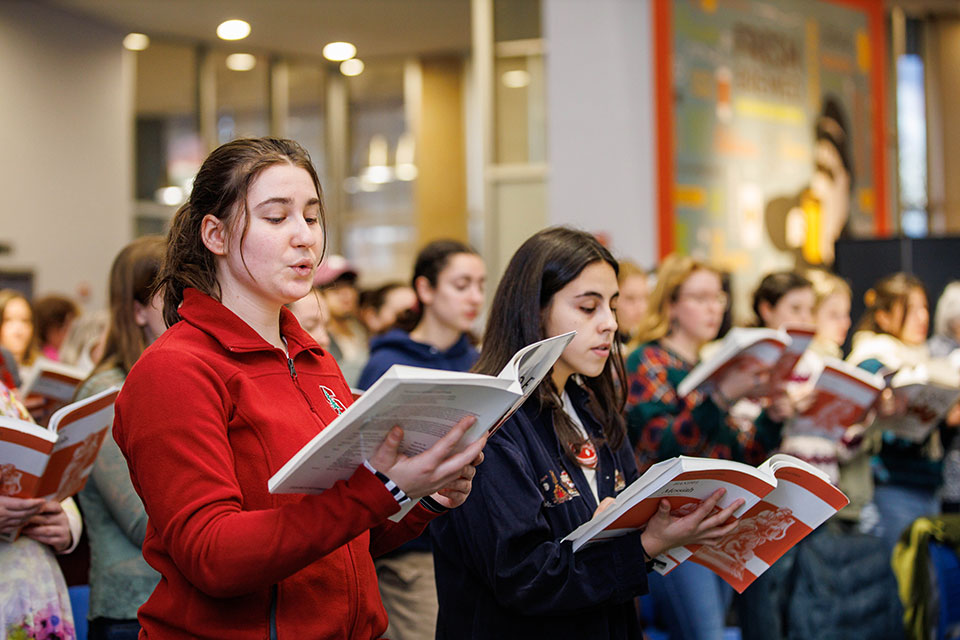 A group of people sing from music books.