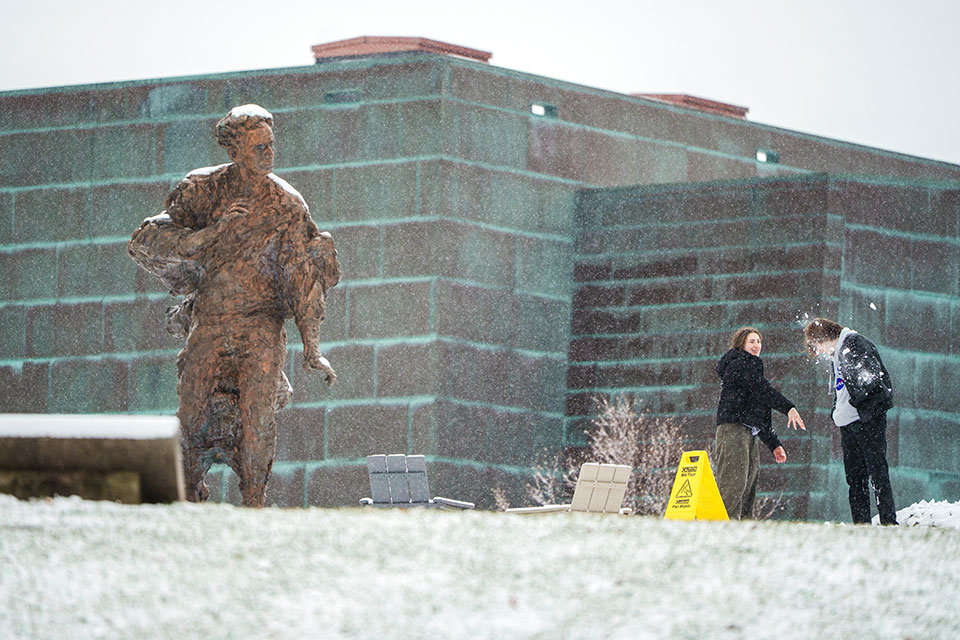 Students have a snowball fight next to the Louis Brandeis statue.