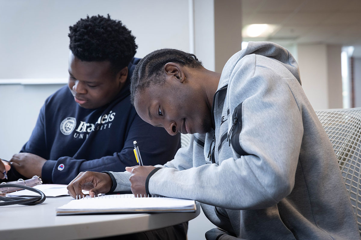 Two students study together at a table in the library.