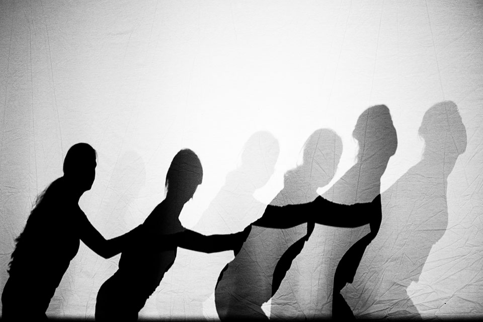 Shadows of dancers against a white wall.