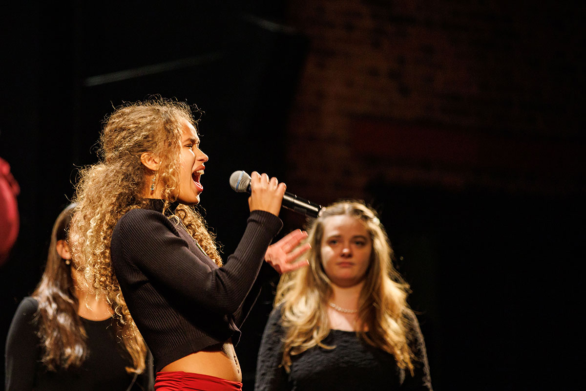 A student sings into a microphone.