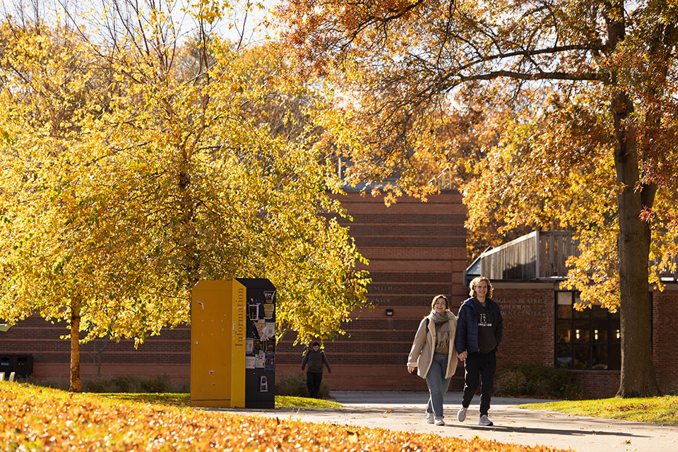 Students walk through fall foliage on campus.