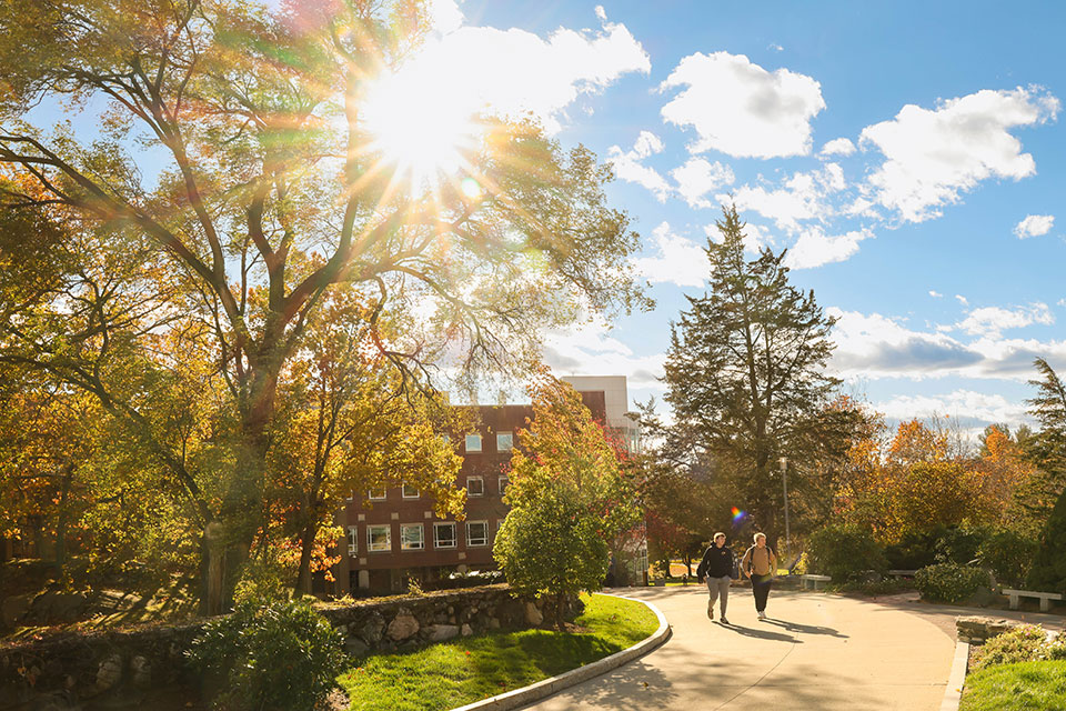 Two students walk on a path on campus during the fall.