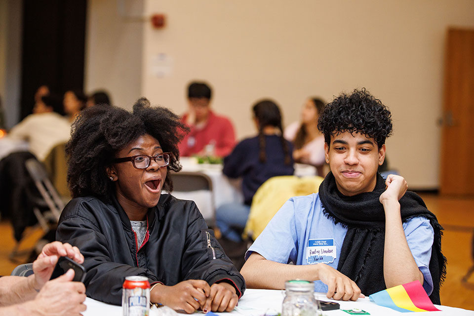 Two students sit at a table and laugh.