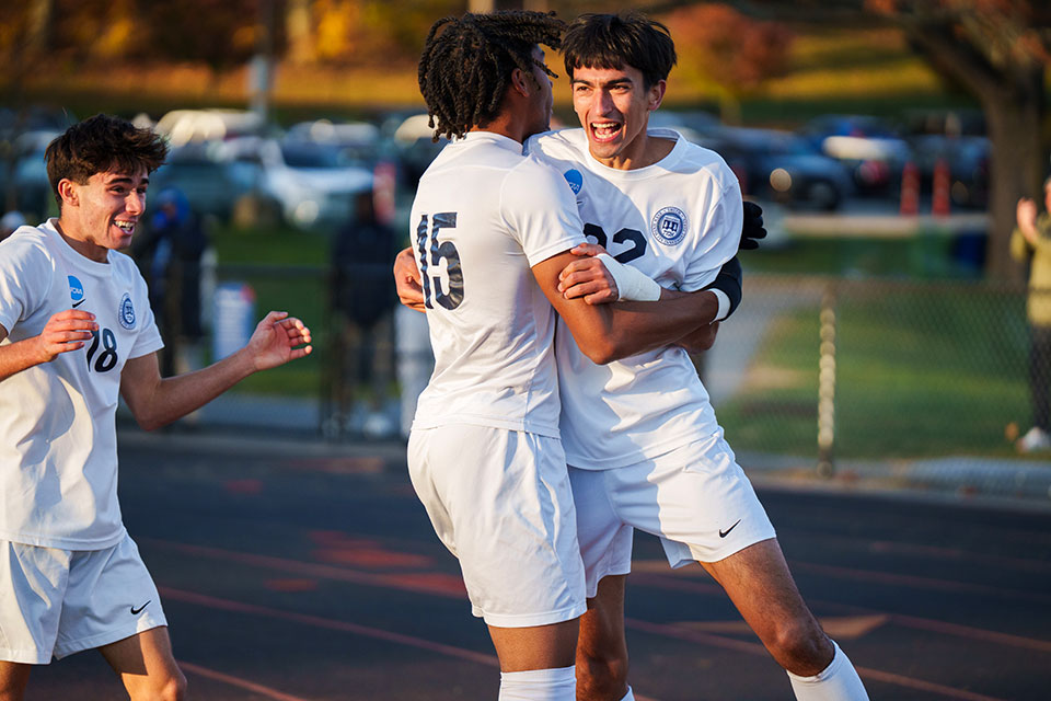 Three soccer players celebrate together.