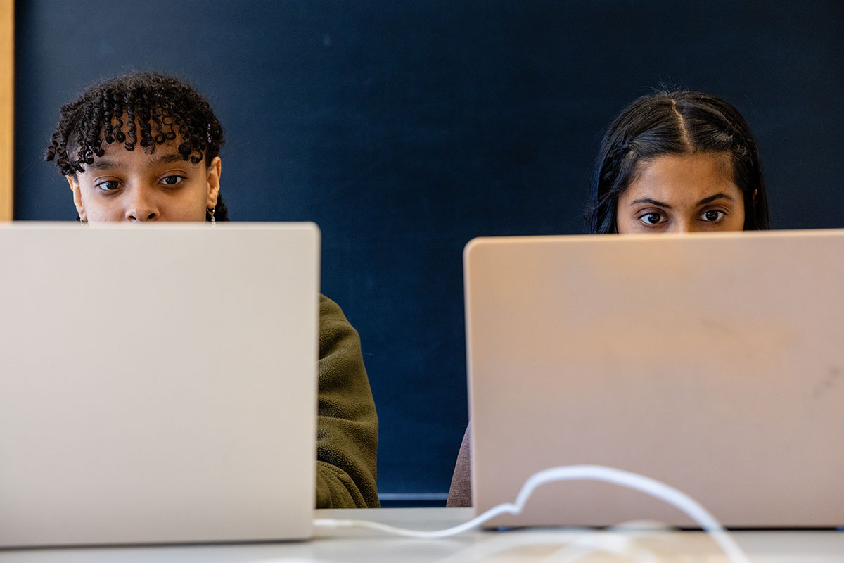 Two students work on their laptops.